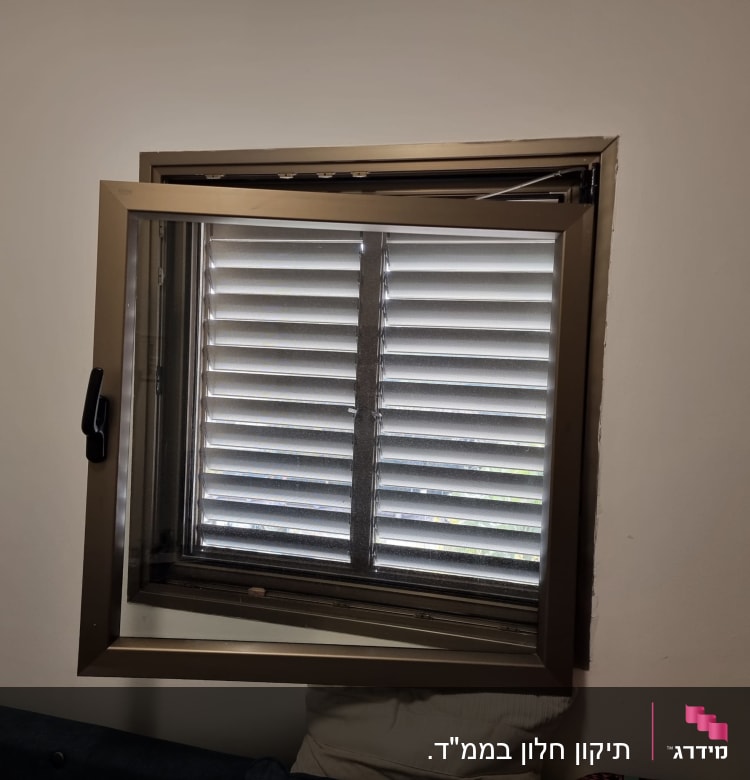 חלון עם תריסים סגורים ומסגרת מתכת פתוחה